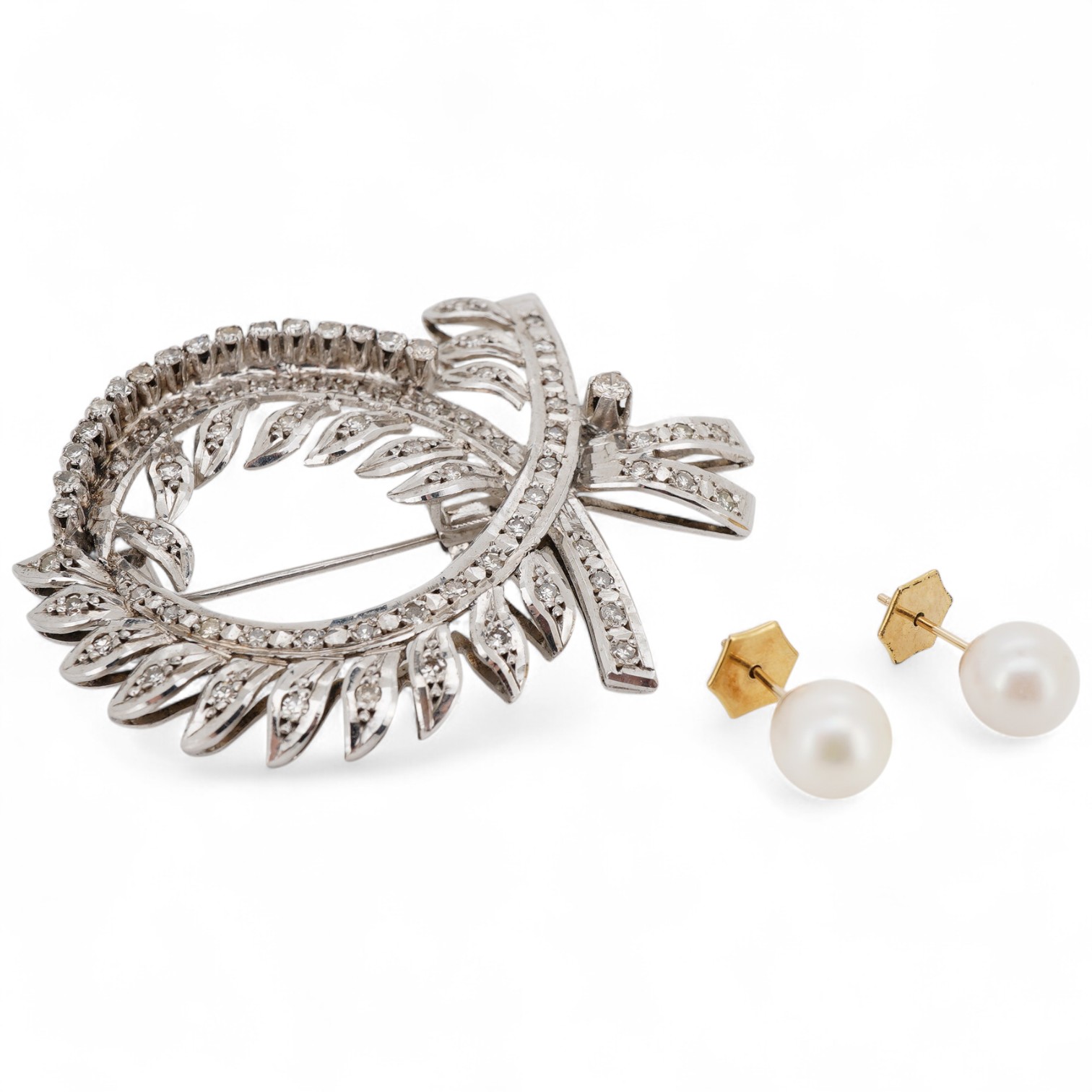 A white metal and diamond cluster set scrolling brooch, 52mm, together with a pair of yellow metal and cultured pearl set ear studs.
